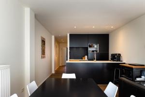a kitchen with black cabinets and a black table and chairs at Maligima in De Panne