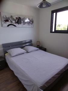 - une chambre dotée d'un grand lit avec des draps blancs et une fenêtre dans l'établissement ANGLET petite Maison à 2 kms des plages et de Biarritz, à Anglet