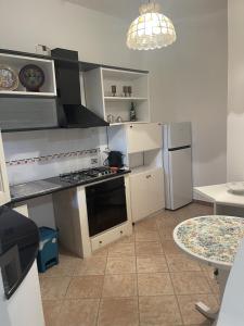 una cucina con piano cottura, frigorifero e tavolo di Appartamento La Guglia a Cala Gonone