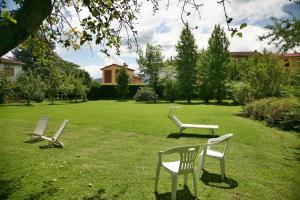 tre sedie sedute nell'erba in un cortile di Villa Camilla - WIDE - EXCLUSIVE POOL a Lucca