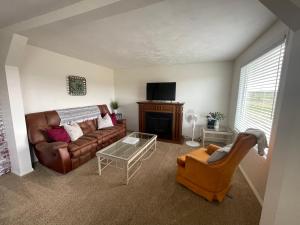 a living room with a brown leather couch and a fireplace at Callie's Cottage in Hatch