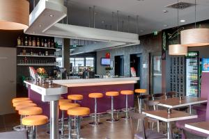 eine Bar in einem Restaurant mit orangefarbenen Stühlen in der Unterkunft MEININGER Hotel Frankfurt Main / Airport in Frankfurt am Main