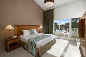een hotelkamer met een bed en een balkon bij Hodelpa Garden Suites - All Inclusive in Juan Dolio