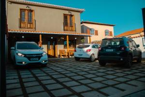 tres autos estacionados en un estacionamiento frente a una casa en Pouso Primavera, en Tiradentes