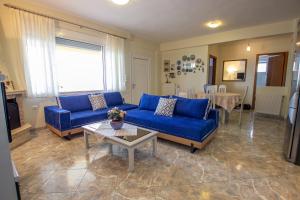 a living room with a blue couch and a table at Kaliva House in Nea Vrasna