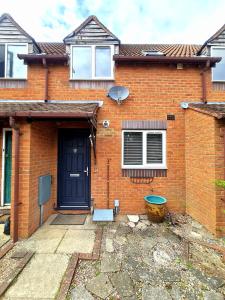 a brick house with a blue door and a window at 2 Bedroom House in Quiet Area, Close to M5 With Free Parking by Glos Homes Ltd in Gloucester