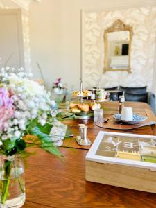 einem Holztisch mit Blumen und einem Teller Essen darauf. in der Unterkunft Demeure de la Garenne in Montmirail