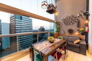 a balcony with a table and a couch at Edificio Summit Pinheiros Best Location in São Paulo Balcony with City Views Pool, Fitness Room and Parking Garage 3 minutes to Subway in Sao Paulo