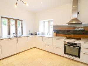a kitchen with white cabinets and a sink at Hollins in Sedbergh
