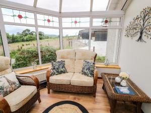 - un salon avec une chaise, une table et des fenêtres dans l'établissement Glebe Farm Cottage, à Newry