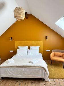 a bedroom with a large bed with an orange wall at Le Gîte de Jean Thevenin, avec parking gratuit in Épernay