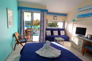 a bedroom with a blue bed with a dress on it at CoCoKreyol - Ti CARAYOU in Les Trois-Îlets