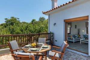 a patio with a table and chairs on a deck at Villa Margini, Aegean Views , Pool Villa, Skopelos in Skopelos Town