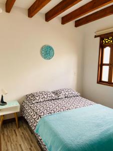 1 dormitorio con 1 cama y reloj en la pared en Casa turquesa, en Villa de Leyva