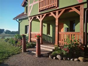 una casa verde con un porche con flores. en Dom pod Srebrnym Żurawiem en Wydminy