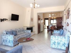 ein Wohnzimmer mit einem Sofa, Stühlen und einem Tisch in der Unterkunft Meltemi Villa in Chrisi Ammoudia