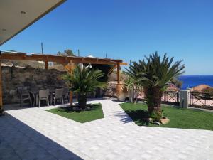 a patio with a table and palm trees and the ocean at The South House, Mountain and Sea View in Paránimfoi
