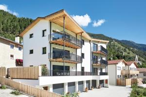 een appartementencomplex met een balkon en bergen op de achtergrond bij ROTUND-Nature_Mountain_Living in Tubre