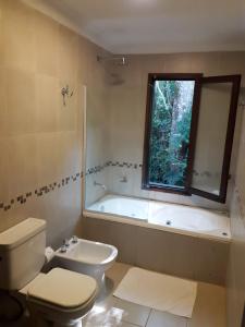 a bathroom with a tub and a toilet and a sink at Selva de Laurel in Puerto Iguazú