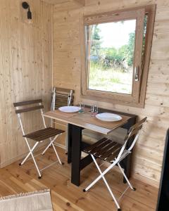una mesa de madera y sillas en una habitación con ventana en Tiny House LA RUCHETTE en Sembadel
