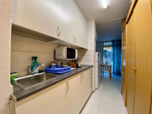 cocina con fregadero y microondas en Apartamento con servicios, piscina y parking privado máx 4 pax, en Salou