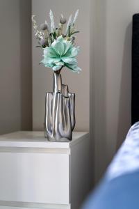 un vaso d'argento con dei fiori sul tavolo. di Apartamento Cabildo Spa 2 a Sanlúcar de Barrameda