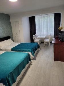 Habitación de hotel con 2 camas, mesa y sillas en Zenlux en Iaşi