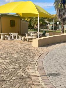 a yellow umbrella and picnic tables and benches at Bela-Bela Pendleberry Grove Unit 3 in Bela-Bela