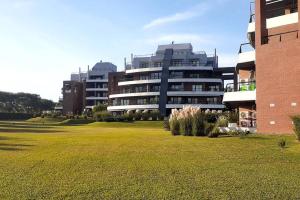 a large building with a grass field in front of it at Fabuloso departamento en complejo residencial in Yerba Buena