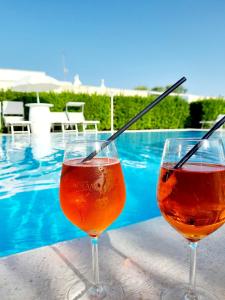 due bicchieri da vino seduti su un tavolo accanto alla piscina di Trulli Nuova Aia Resort ad Alberobello