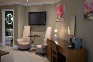 Zimmer mit 2 Stühlen und einem Schreibtisch mit einem TV in der Unterkunft Best Western Plus Centurion Hotel in Midsomer Norton