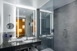 a bathroom with a sink, mirror, and bathtub at Radisson Blu Hotel Rostock in Rostock