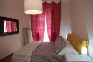 トリノにあるAppartamento Elenaのベッドルーム1室(ベッド1台付)、赤いカーテン付きの窓が備わります。