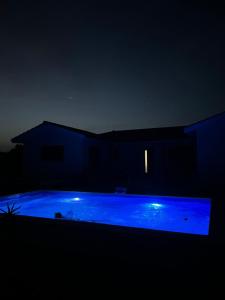 a blue swimming pool at night with a house at Havre de paix in Fontet