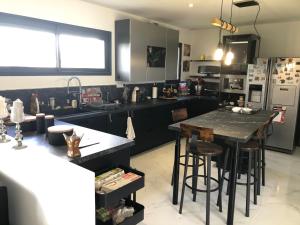 a kitchen with black cabinets and a table with bar stools at Havre de paix in Fontet