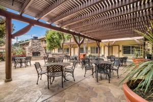 een patio met tafels en stoelen onder een pergola bij Best Western Corona Hotel & Suites in Corona