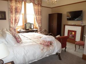 a bedroom with a bed and a tv and a fireplace at Camfield House in Thurso