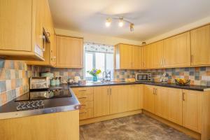 a large kitchen with wooden cabinets and a window at Ty Nant in Llanrwst