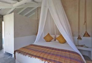 a bedroom with a bed with a mosquito net at Casa de Cantoneiros, Comporta in Torroal