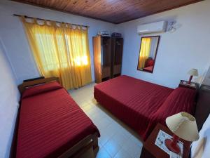 a bedroom with two red beds and a mirror at El Ámbar in Colón
