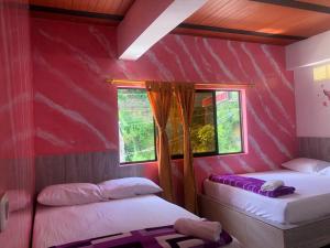 2 camas en una habitación con paredes rosas y ventana en Hotel Jireh - San Carlos Ant, en San Carlos