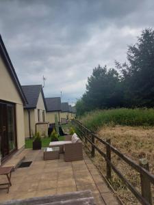 a patio with a couch and chairs next to a house at 10 The Parklands - Cosy Bungalow in Cornwall in Kilkhampton