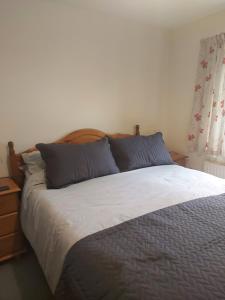 1 dormitorio con 1 cama grande con almohadas azules en 10 The Parklands - Cosy Bungalow in Cornwall, en Kilkhampton