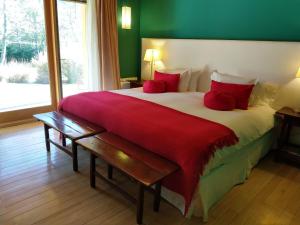 um quarto com uma cama grande e almofadas vermelhas em Rio Hermoso Hotel De Montaña em San Martín de los Andes