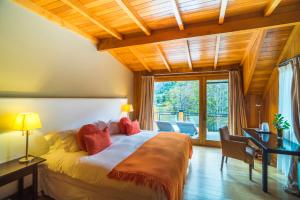 um quarto com uma cama, uma secretária e uma janela em Rio Hermoso Hotel De Montaña em San Martín de los Andes