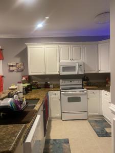 a kitchen with white cabinets and a stove and microwave at Golfers & Families Dream Vacation! Patio, Pool, 4 Miles to Everything ! Spacious Condo Stocked with all You Need! in Myrtle Beach