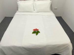 a white bed with a red flower on it at AYDIZ APARTMENTS in Nadi