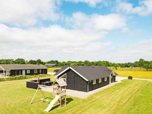 una casa con tetto nero e parco giochi di 10 person holiday home in Ansager ad Ansager