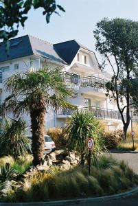 a large white building with a palm tree in front of it at Résidence Ker Juliette in Pornichet