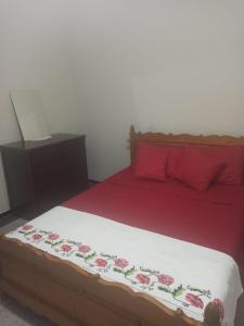 1 dormitorio con 1 cama con sábanas rojas y almohadas rojas en Quartier Anne Marie, en Temara